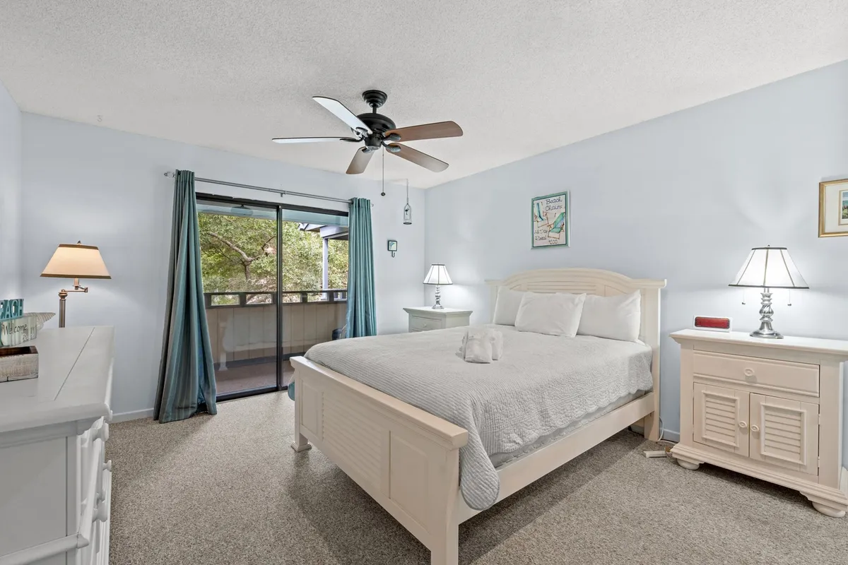 A tranquil bedroom with a plush Queen bed as the focal point, flanked by matching nightstands and softly lit lamps. Gentle natural light filters through the curtained window, and a dresser provides additional storage. The mood is calming, and the space looks inviting for relaxation or rest.
