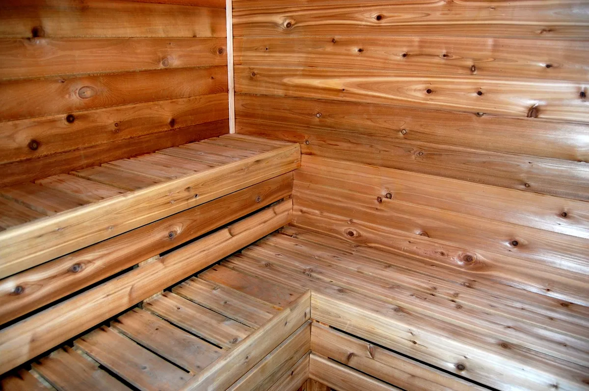 This calming interior shot features a traditional sauna with wooden benches and walls, creating a warm and inviting environment for relaxation and wellness routines. The simple, uncluttered setting emphasizes moments of reflection and self-care.