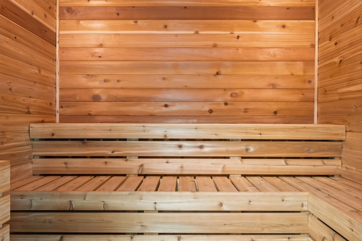 A serene interior sauna featuring cedar wood paneling and wooden benches, radiating a calming, spa-like atmosphere.